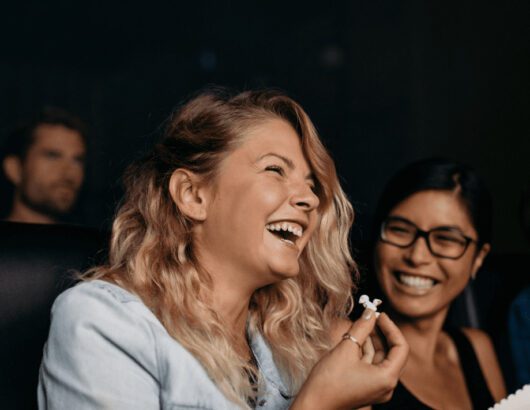 Two Girls Enjoying and Having Popcorn in a Theatre